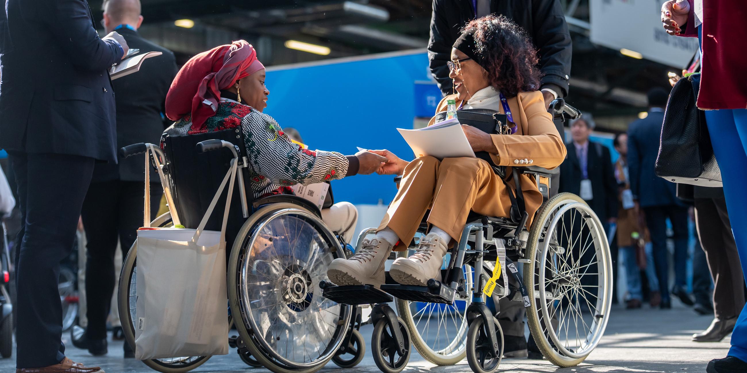 Besucherinnen im Rollstuhl sind auf dem Weltgipfel für Menschen mit Behinderungen unterwegs.