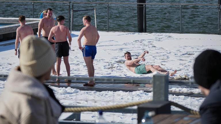  Menschen genießen einen sonnigen und frostigen Tag, nachdem sie in der Sauna des öffentlichen Bades in Helsinki geschwitzt haben.