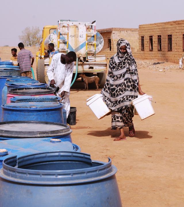 Menschen füllen in Khartum Wasserbehälter an einer kostenlosen Ausgabestelle.