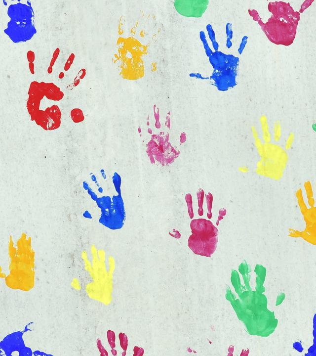 Bunte Handabdrücken auf einer bemalte Wand einer Kindertagesstätte.