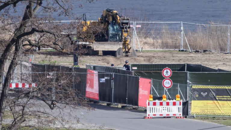 Mitarbeiter der Kampfmittelbeseitigung stehen auf der Baustelle an der abgerissenen Carolabrücke an der Fundstelle der Bombe.