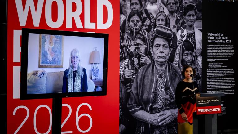 Die Fotografin Carol Guzy spricht per Videobotschaft (links) während des World Press Photo-Wettbewerbs 2026. Guzy gewinnt mit ihrem Foto „Separated by ICE“. 