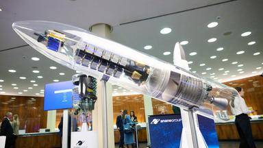 Ein Modell eines Raumschiffes. Es ist durchtig und steht mitten im Weltraumkongress.