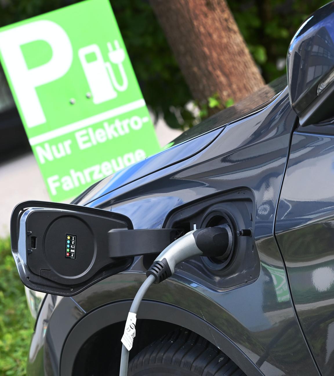 E-Auto wird auf einem Parkplatz nur fuer Elektro-Fahrzeuge geladen,Stecker waehrend dem Ladevorgang an einem E-Auto