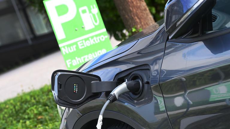 E-Auto wird auf einem Parkplatz nur fuer Elektro-Fahrzeuge geladen,Stecker waehrend dem Ladevorgang an einem E-Auto
