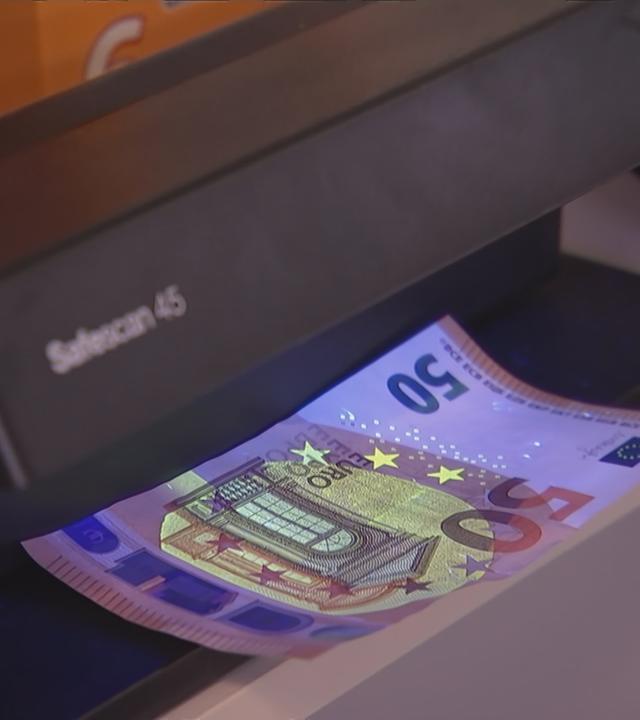 50-Euro-Schein wird auf Echtheit im Automatem geprüft.