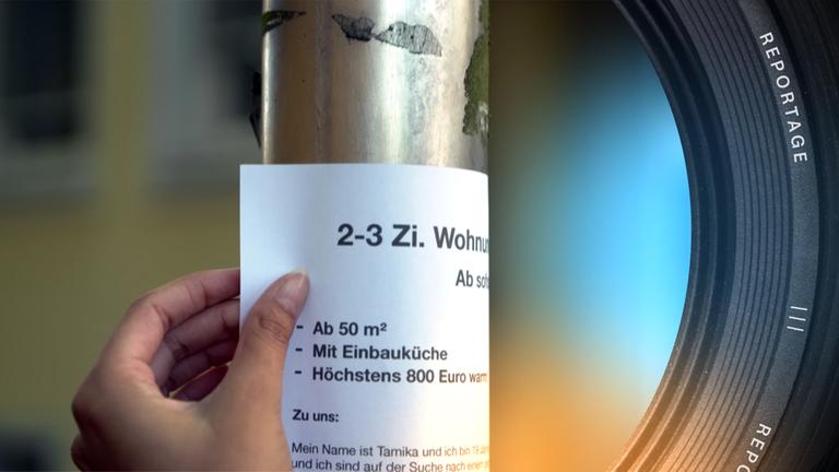 Eine Person befestigt einen Wohnungsgesuchszettel an einer metallenen Stange.