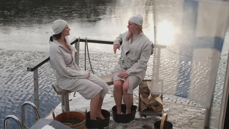 Auf dem Bild sieht man zwei Frauen auf mobiler Sauna auf der Spree.
