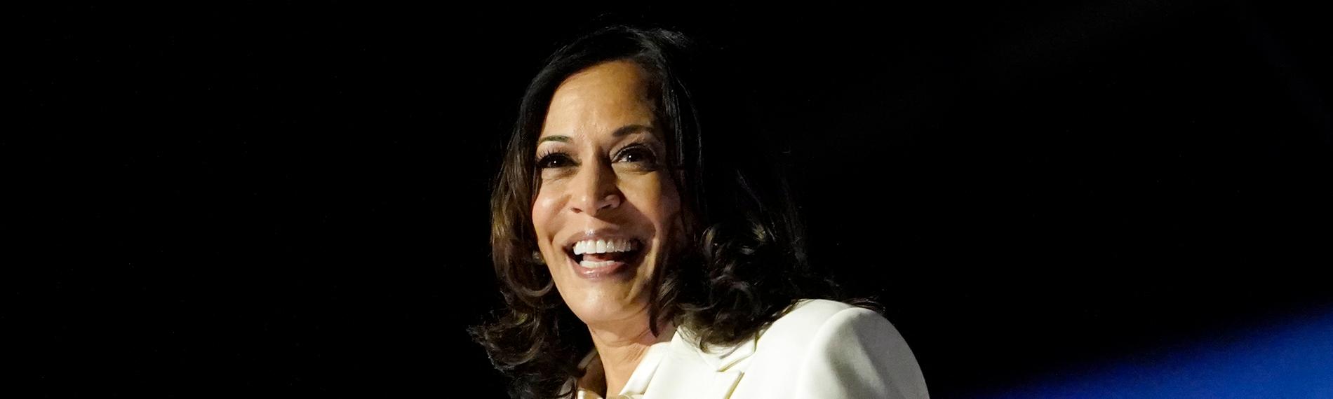 Kamala Harris steht an einem Rednerpult. Sie lächelt. 
