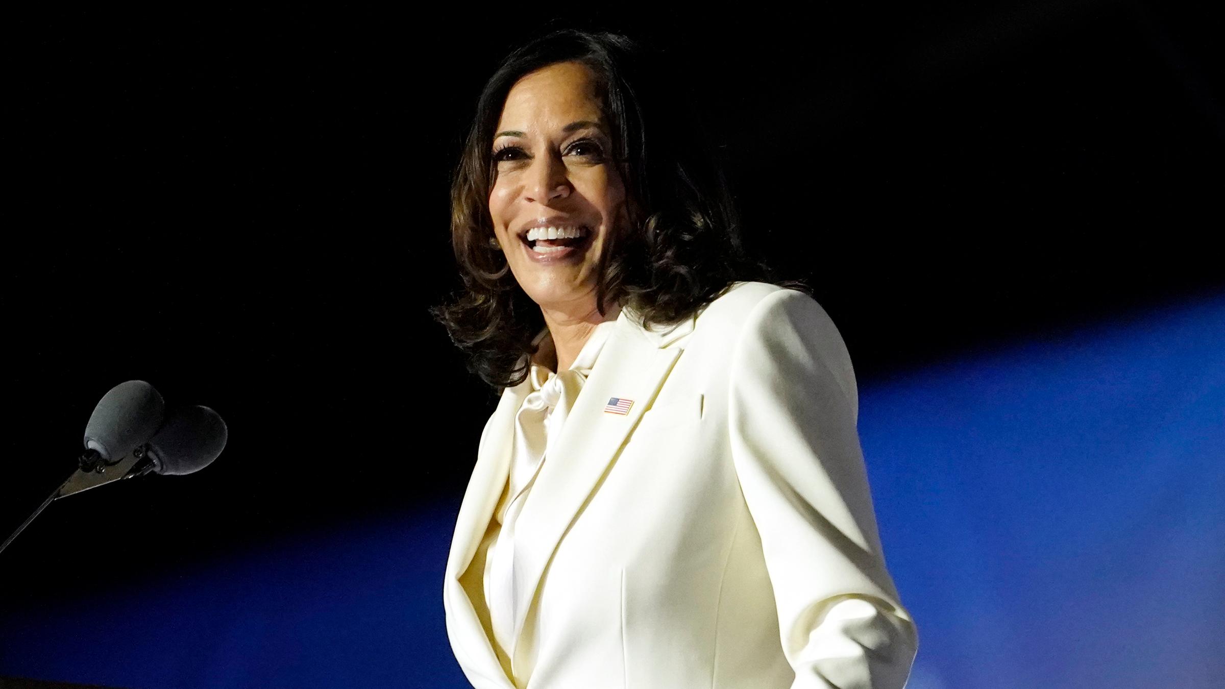 Kamala Harris steht an einem Rednerpult. Sie lächelt. 