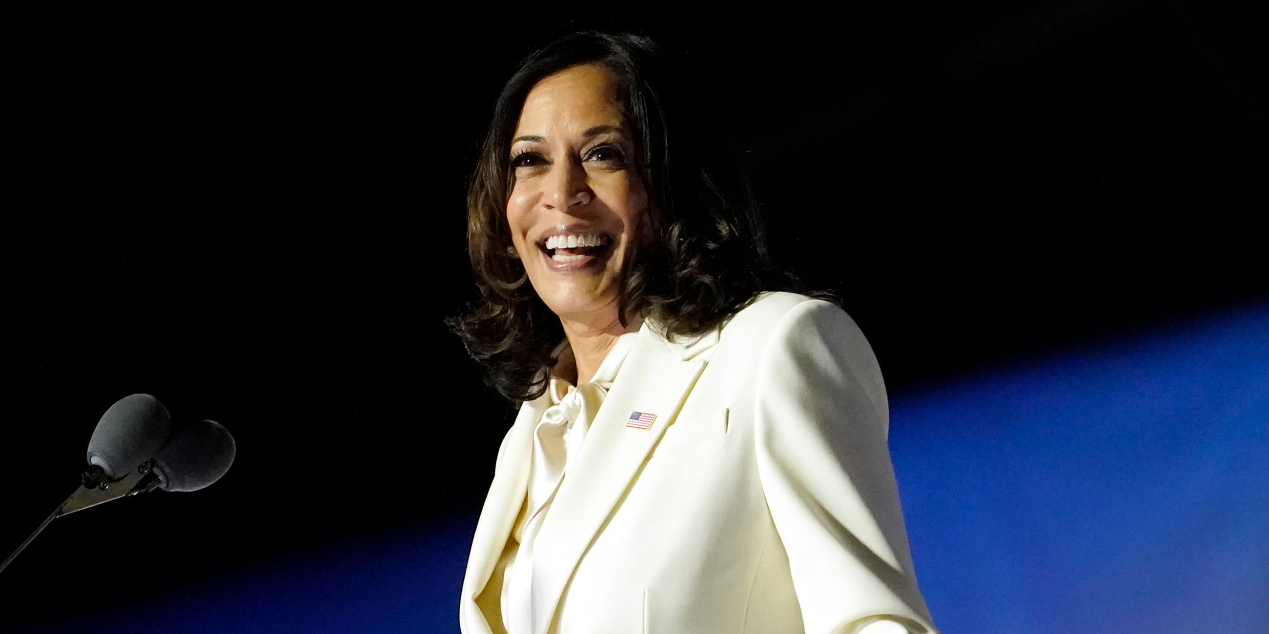 Kamala Harris steht an einem Rednerpult. Sie lächelt. 