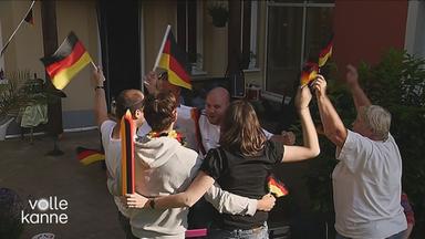 Menschen mit Deutschland-Fahnen springen im Kreis und jubeln