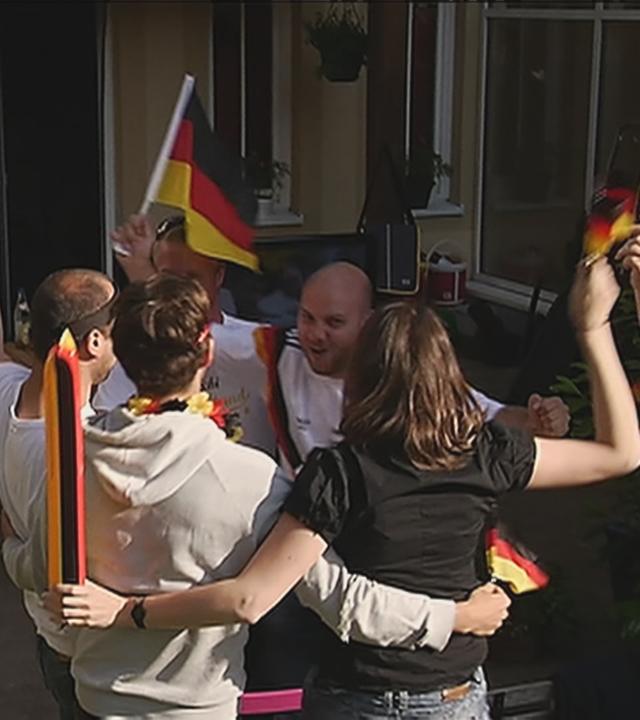 Menschen mit Deutschland-Fahnen springen im Kreis und jubeln