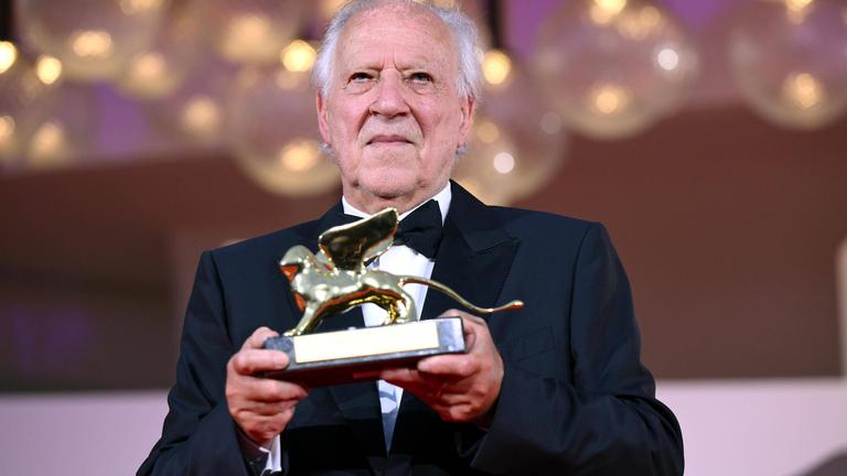 Werner Herzog hält einen Ehrenpreis der Filmfestspiele in der Hand.