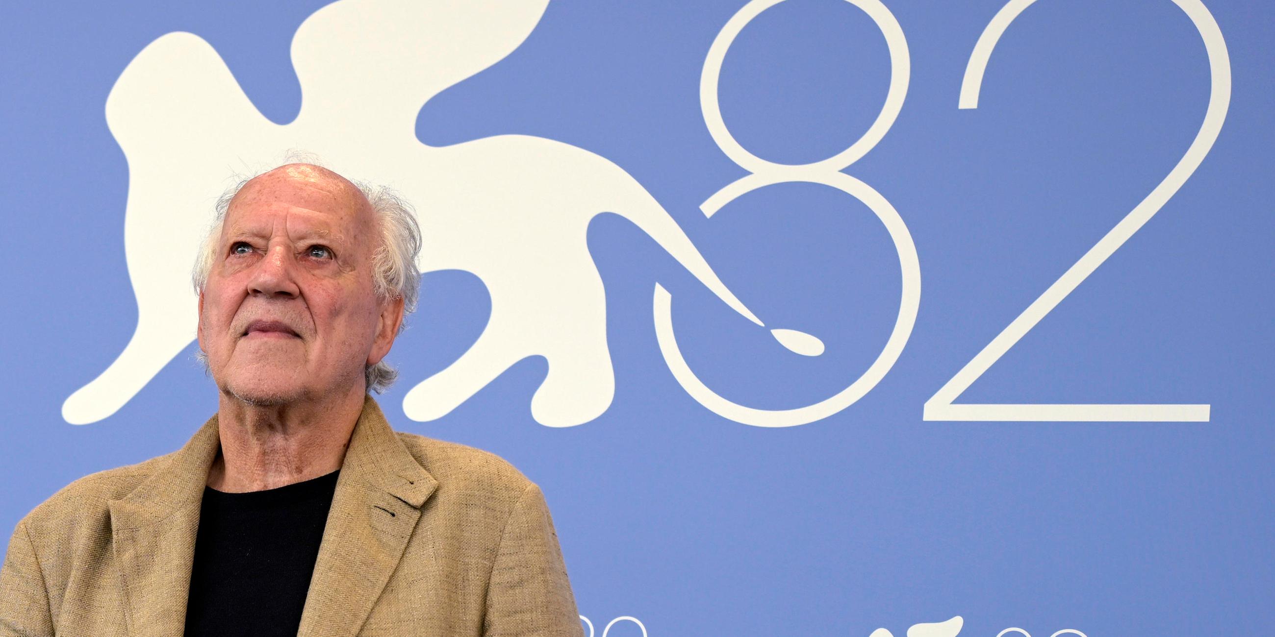 Werner Herzog bei den Filmfestspielen in Venedig. Hinter ihm steht eine große 82 an der Wand, da es die 82. Filmfestspiele sind