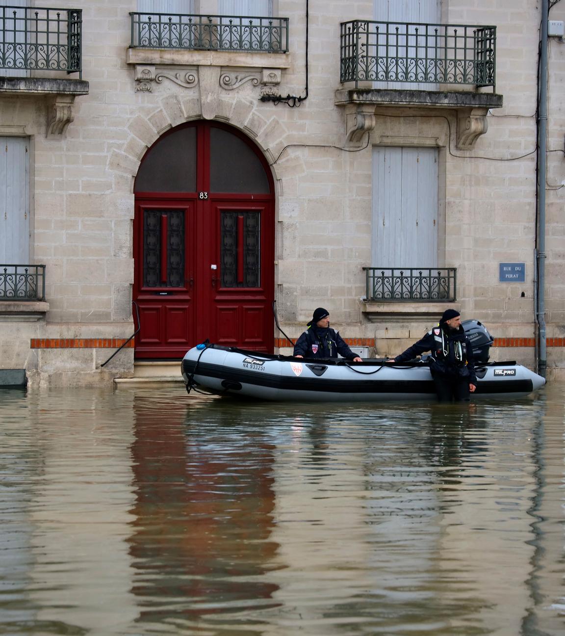 18.02.2026, Frankreich, Saintes: Polizeibeamte stehen in einer überfluteten Straße in Saintes, als schwere Überschwemmungen den Westen Frankreichs inmitten des Sturms Pedro treffen.
