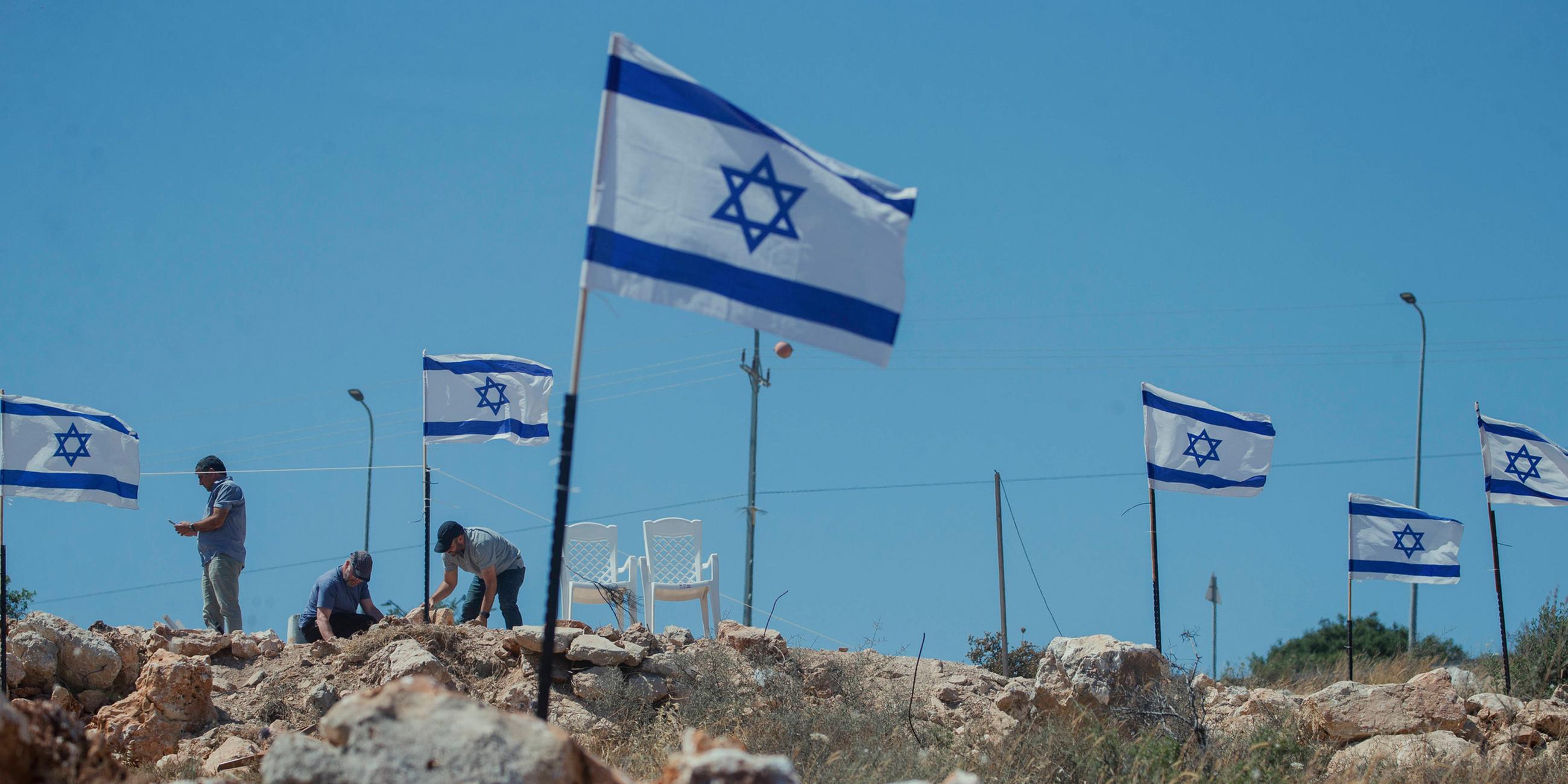 Siedler hissen Fahnen in Bruqin: Jüdische Siedler hissen am 23. Mai 2025 israelische Flaggen auf palästinensischen Häusern im Dorf Bruqin im nördlichen Westjordanland.