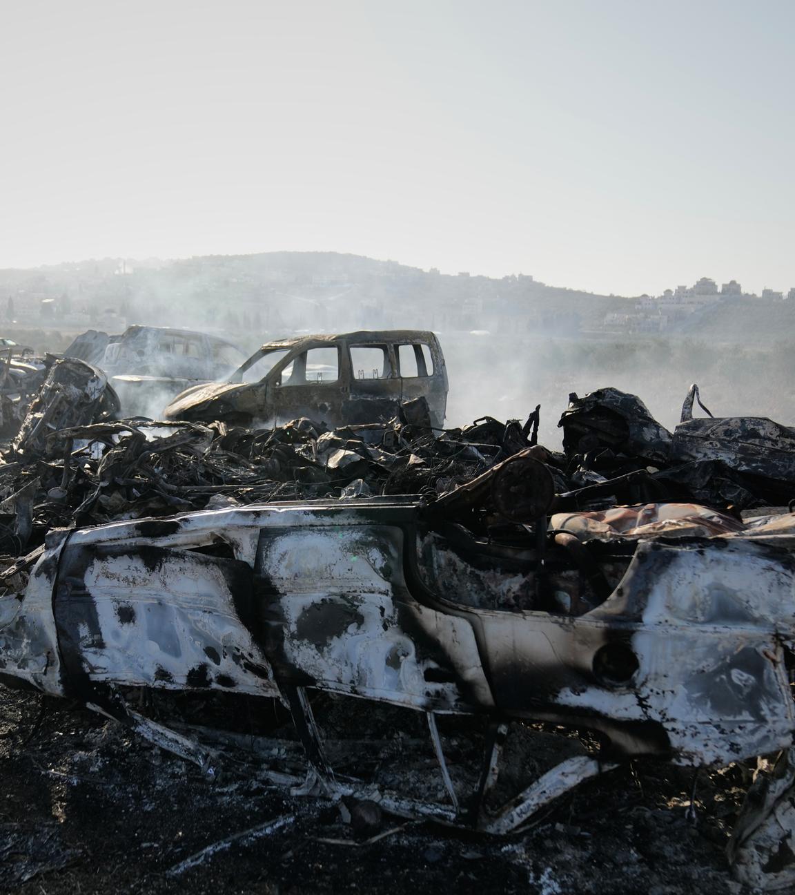 Rauch steigt von verbrannten Autos auf einem Schrottplatz auf.