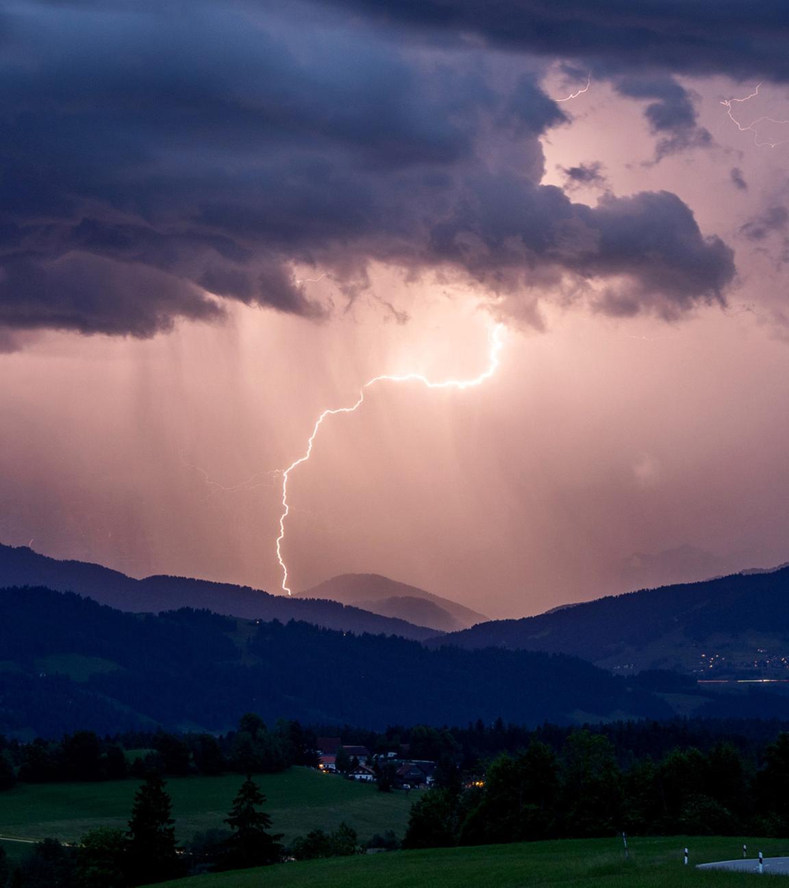 Blitze entladen sich über den Alpen während eines aufziehenden Gewitters am Abend hinter der St. Hubertus Kapelle in Scheidegg. (Archiv)