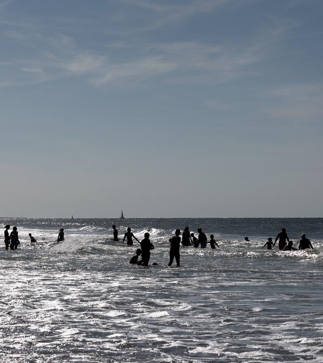 Menschen vergnügen sich im Wasser am Nordstrand auf der Insel Norderney.