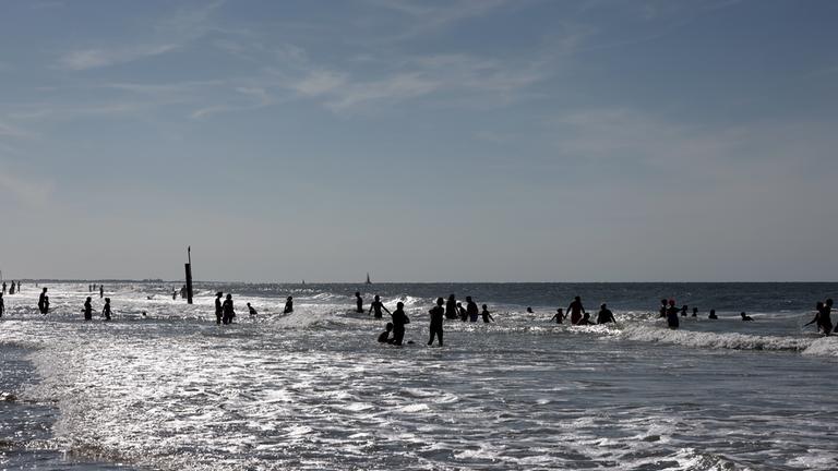 Menschen vergnügen sich im Wasser am Nordstrand auf der Insel Norderney.