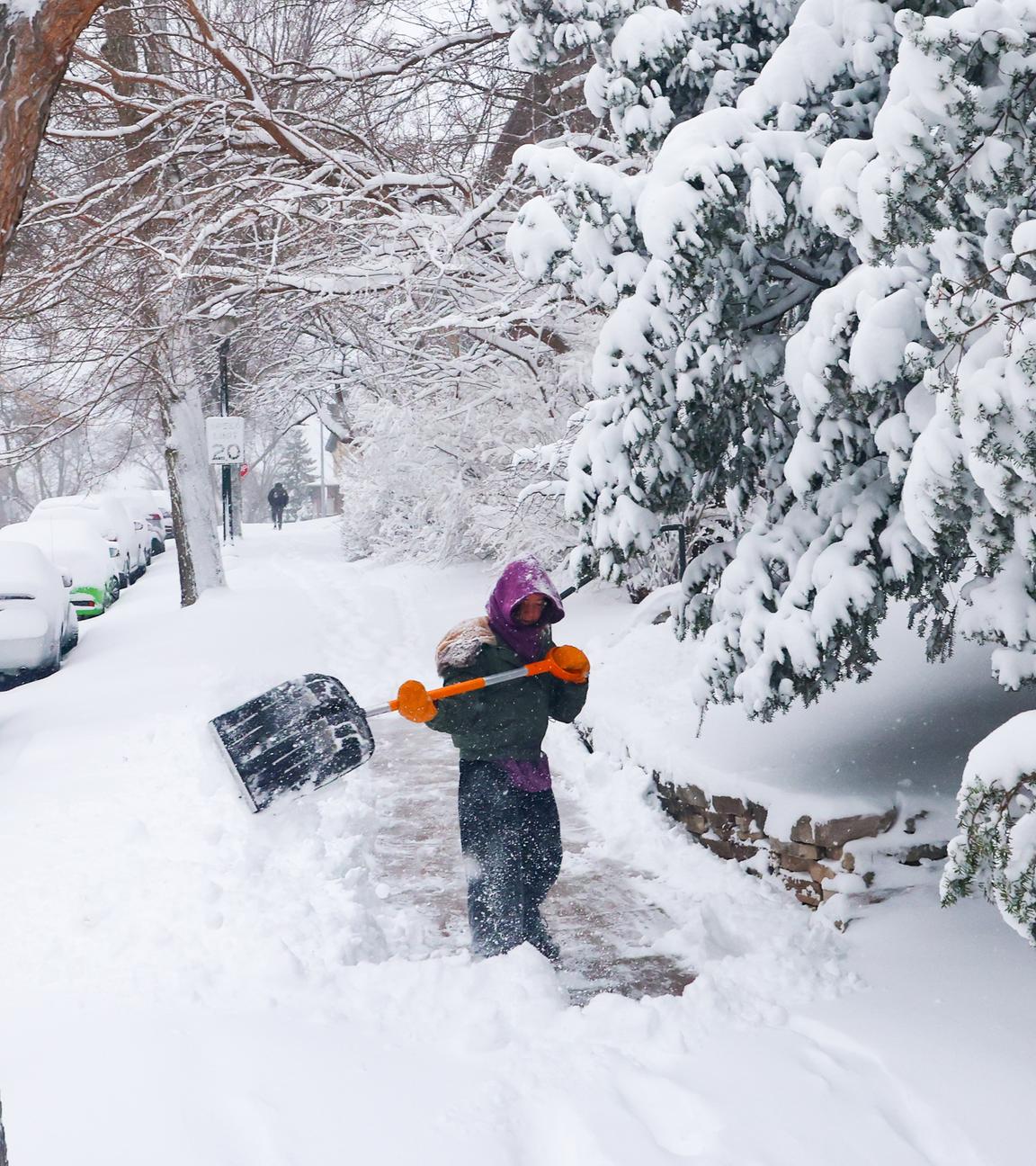 Tess Durham schaufelt am Montag in Madison in Wisconsin Schnee von einem Bürgersteig.