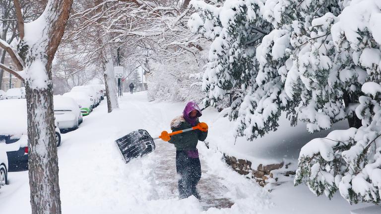 Tess Durham schaufelt am Montag in Madison in Wisconsin Schnee von einem Bürgersteig.