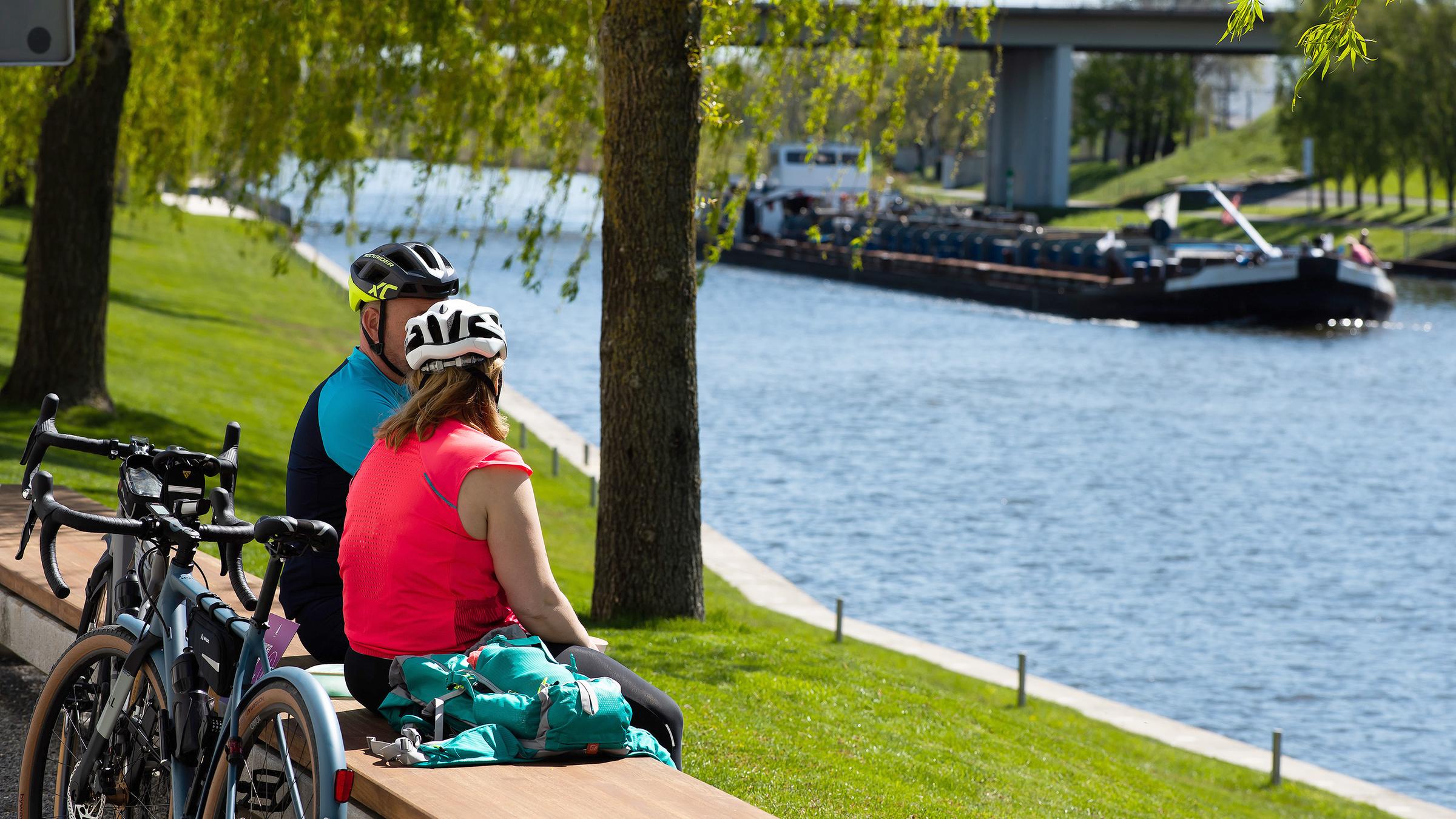 Zwei Radfahrer genießen das sommerliche Wetter bei einer Pause am Mittellandkanal.