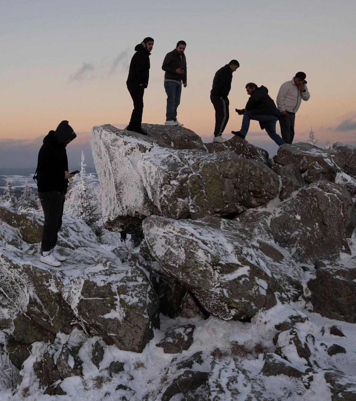 Vom Brunhildisfelsen aus blicken Spaziergänger im letzten Licht des Tages auf dem Feldbergplateau in die verschneite Landschaft.