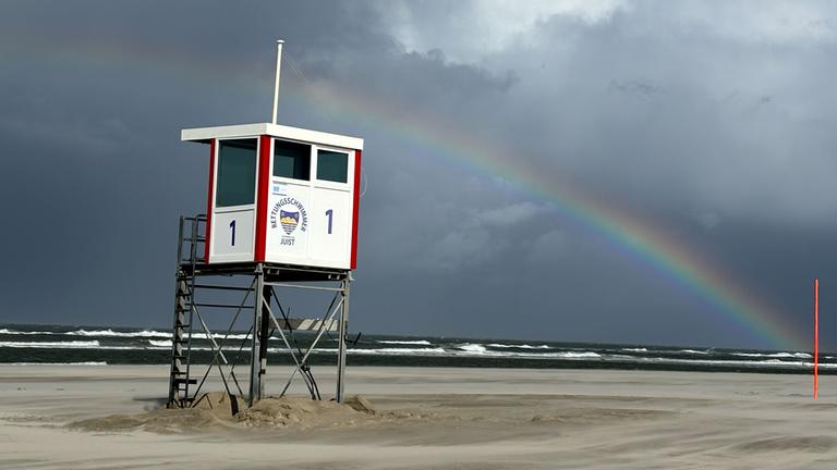 Ein Regenbogen steht an einem Himmel voll dunkler Wolken über der Nordsee und über der Insel Juist. Orkanartige Böen mit teils über 100 Kilometern pro Stunde ziehen über Teile von Norddeutschland. Dazu könne es Dauerregen sowie Gewitter geben, teilte der Deutsche Wetterdienst (DWD) mit.