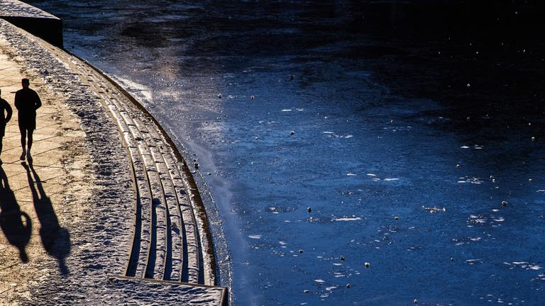 Zwei Personen Joggen entlang der gefrohrenen Spree am 11.01.2026 in Berlin.