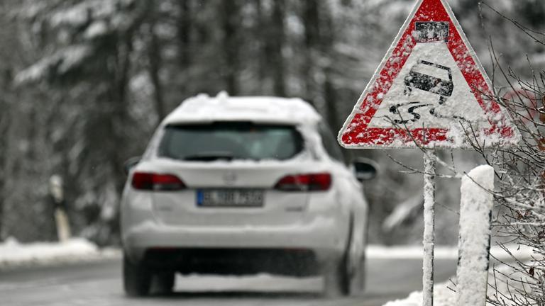 Ein Auto fährt bei winterlichen Verhältnissen über eine Landstraße.