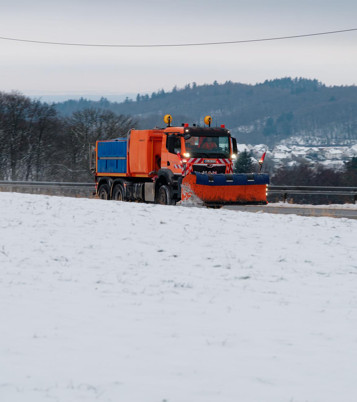  Ein Schneeräumfahrzeug fährt durch die schneebedeckte Landschaft des Odenwalds. 
