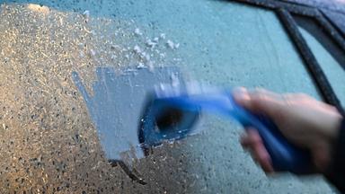 18.11.2025, Baden-Württemberg, Stuttgart: Ein Mann kratzt am Morgen eine Autoscheibe von einer Eisschicht frei.