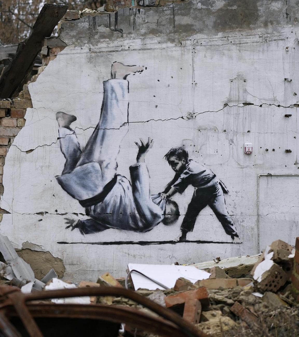 Ein Kunstwerk, das vermutlich von dem bekannten Graffitikünstler Banksy stammt, an einem beschädigten Gebäude in der Nähe von Kiew.