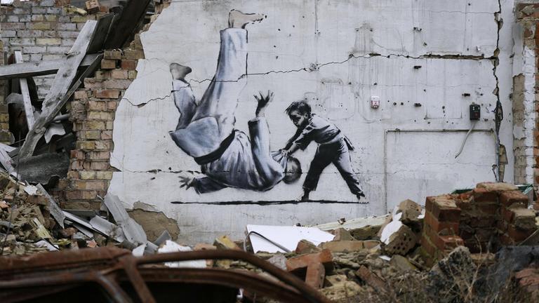 Ein Kunstwerk, das vermutlich von dem bekannten Graffitikünstler Banksy stammt, an einem beschädigten Gebäude in der Nähe von Kiew.