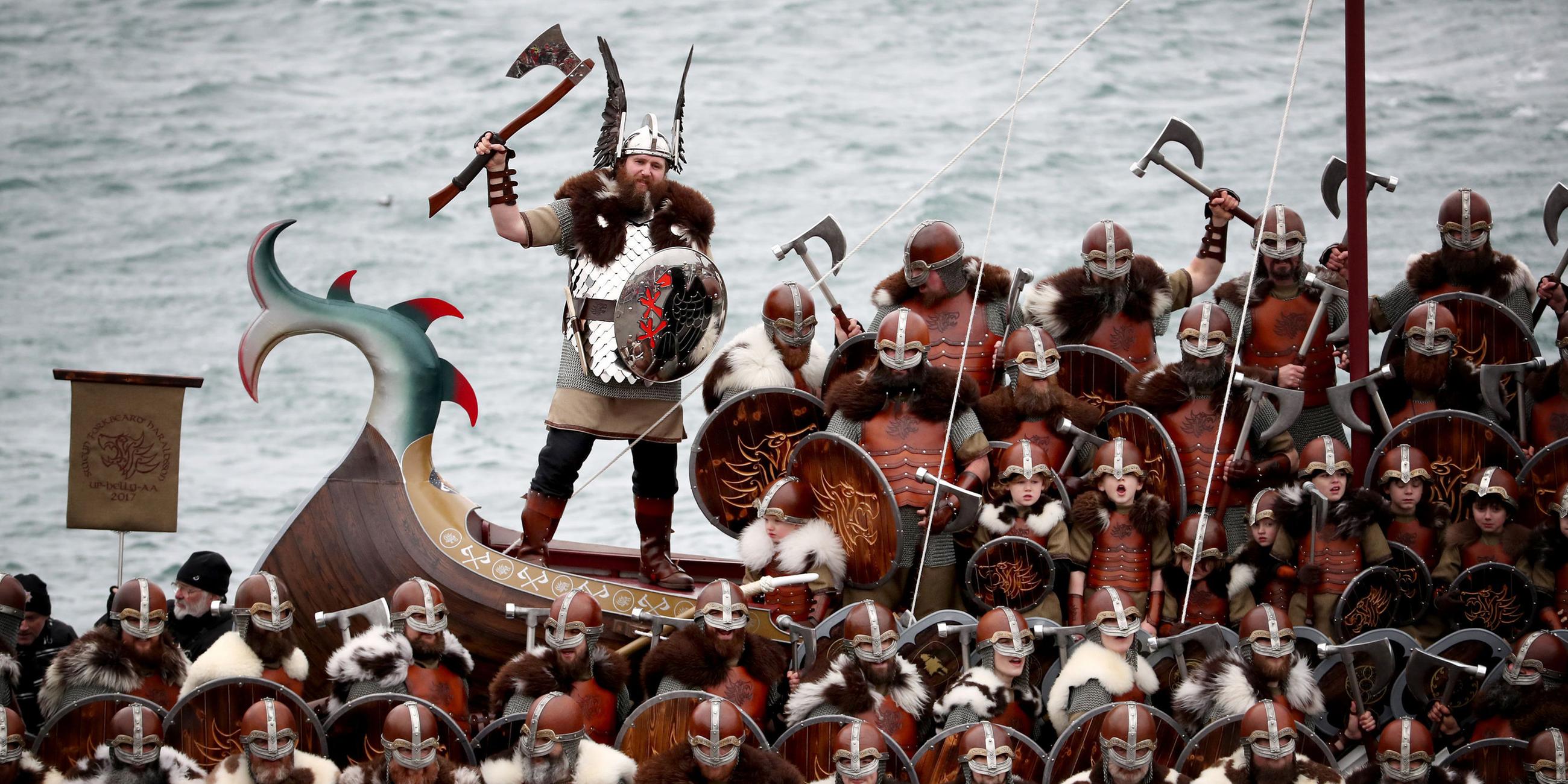 Mitglieder des Vereins "Jarl Squad", verkleidet als Wikinger, posieren für ein Gruppenfoto vor einer Galeere auf den Shetland-Inseln beim jährlichen Wikinger-Festival "Up Helly Aa"
