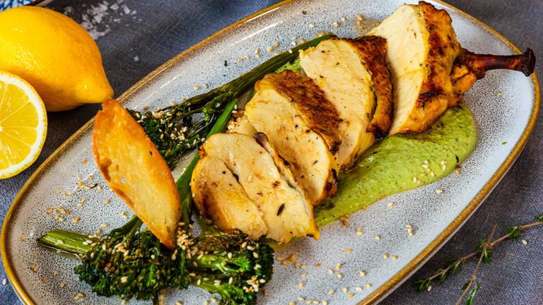 Teller mit aufgeschnittenem gebackenen Hähnchen auf Basilikumsauce mit Brokkoli und Ciabatta-Chips