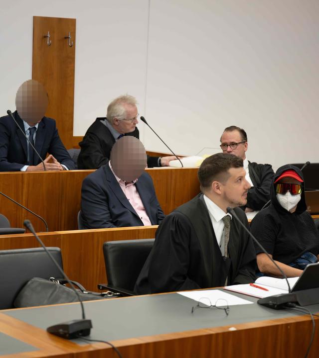 Angeklagte und Anwälte sitzen im Gerichtssaal.