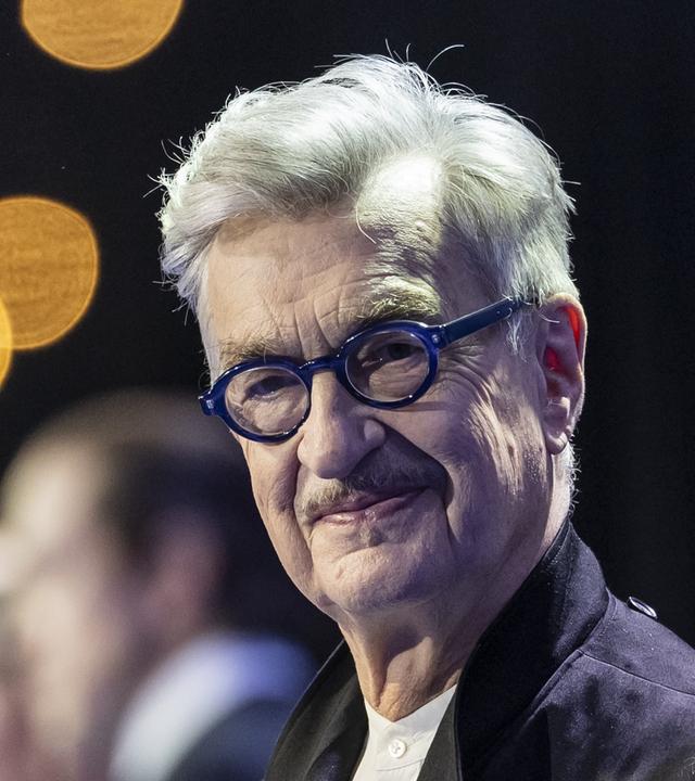 Wim Wenders, deutscher Regisseur, schaut in die Kamera. Er trägt eine runde dunkelblaue Brille.