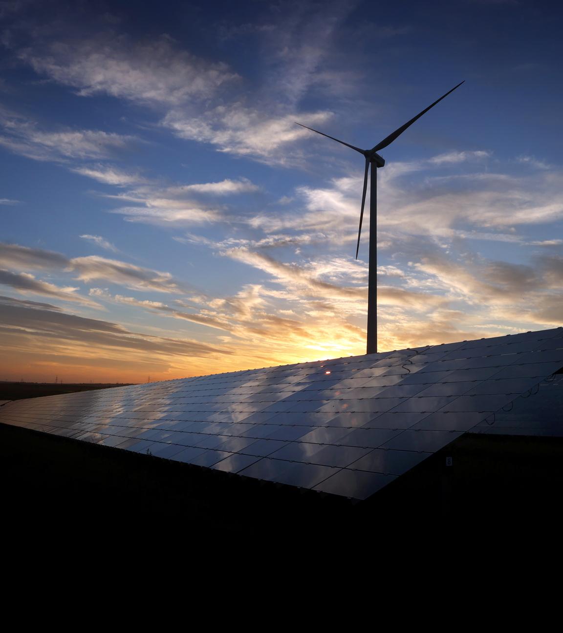 Ein Windkraftanlage und im Vordergrund ein Solarpark bei Sonnenuntergang 