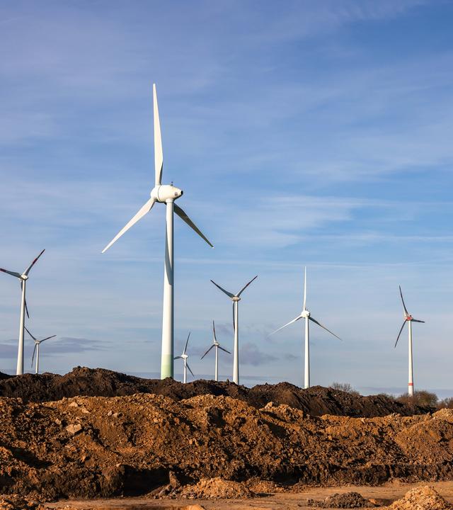 Sachsen-Anhalt, Wettin-Löbejün: Windräder stehen hinter Erdhaufen am Rande eines Baufelds