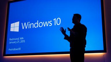 Microsoft Executive Vice President Terry Myerson beid er Präsentation von Windows 10 im Januar 2015. Man sieht nur seine Umrisse vor der blauen Präsentationsfolie.