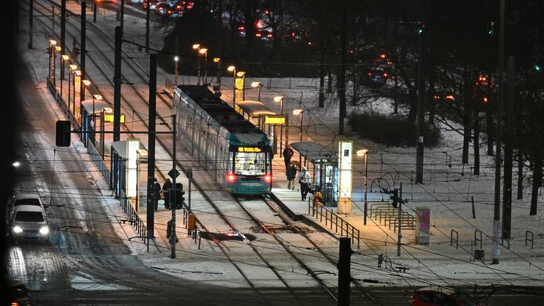 Nahe des Alexanderplatzes liegt noch Schnee auf den Straßen und zwischen den Schienen, während eine Tram kommt und Fußgänger unterwegs sind.