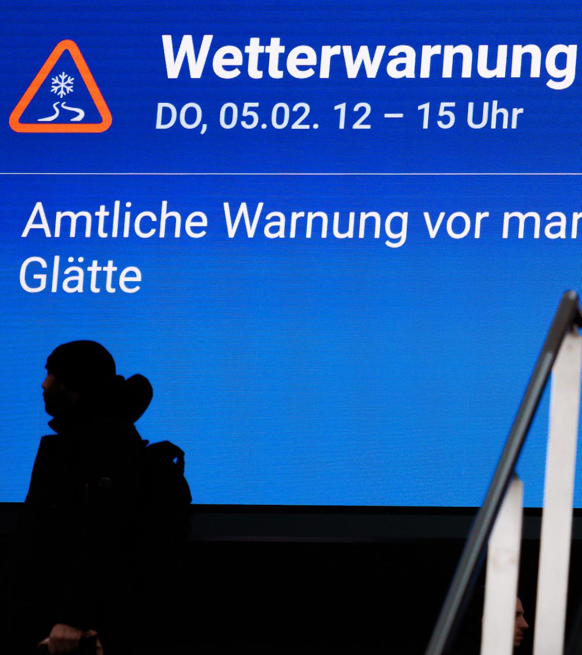 Reisende gehen an einem Display mit dem Hinweis Wetterwarnung im Berliner Hauptbahnhof vorbei. 