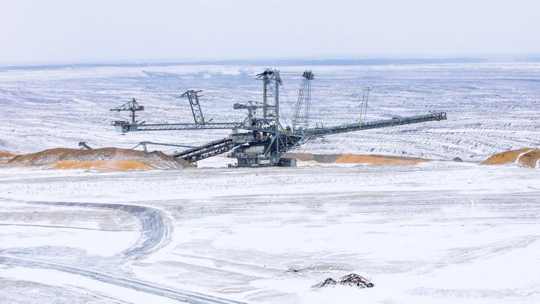 Ein Absetzer steht in der schneebedeckten Landschaft vom Tagebau Nochten