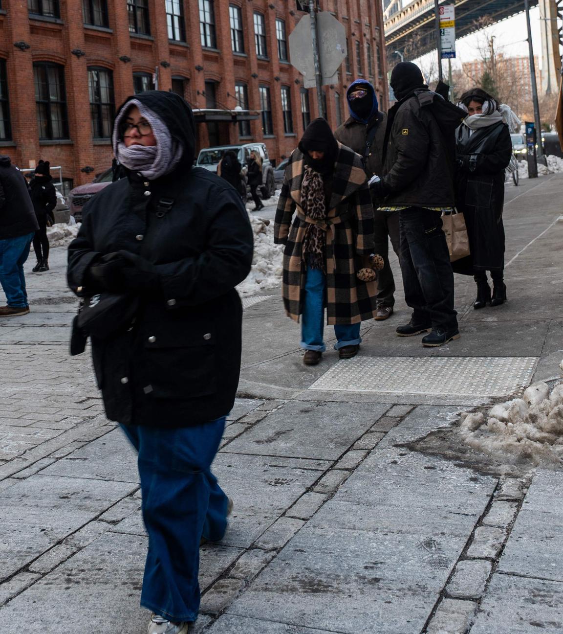 Menschen in dicker Winterkleidung gehen durch eine verschneite Straße im New Yorker Stadtteil Brooklyn.