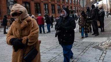 Menschen in dicker Winterkleidung gehen durch eine verschneite Straße im New Yorker Stadtteil Brooklyn.