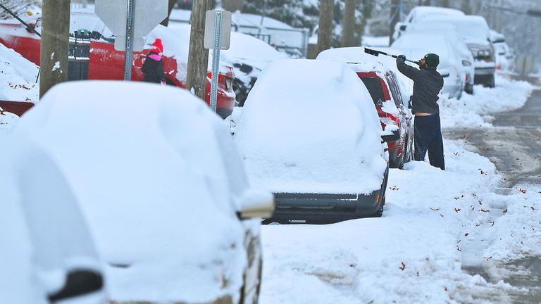 Archiv: Ein Anwohner schaufelt Schnee von einem Auto an einer Straße in Blakely, aufgenommen am 15.11.2018