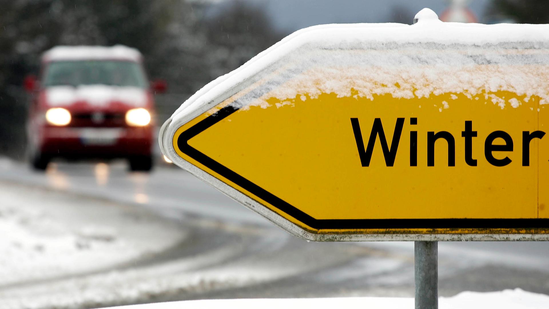 Ein Auto steht an einer schneebedeckten Kreuzug